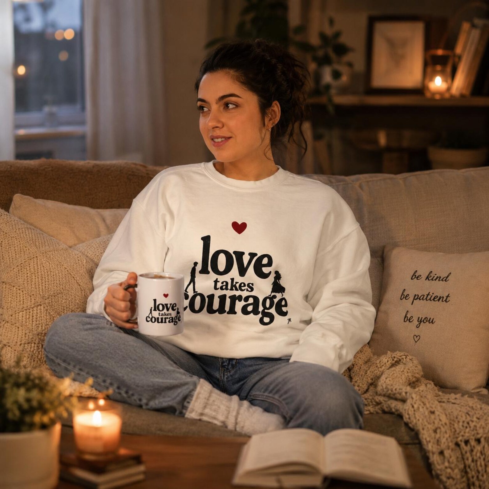 Love Takes Courage cream sweatshirt worn in a softly lit reading nook